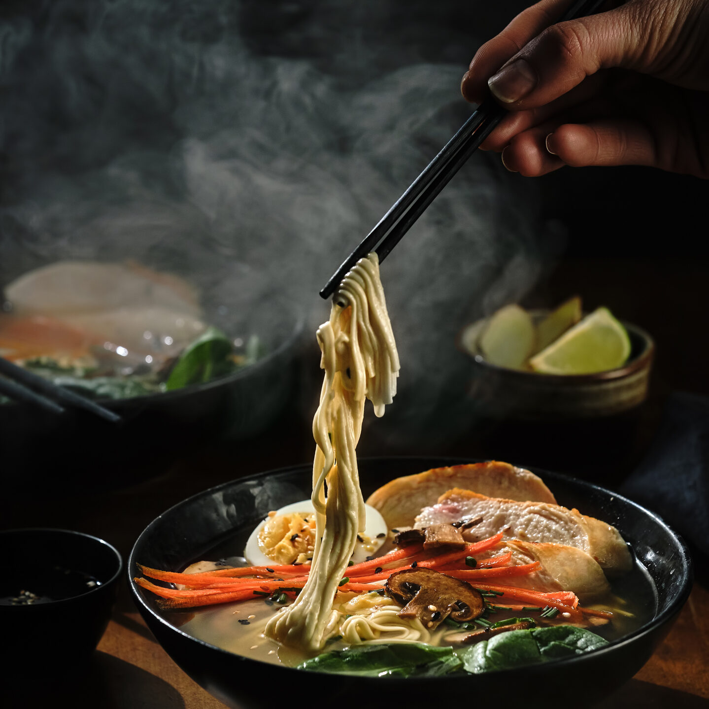Hand with chopsticks takes noodles of ramen soup. Traditional Asian cuisine.